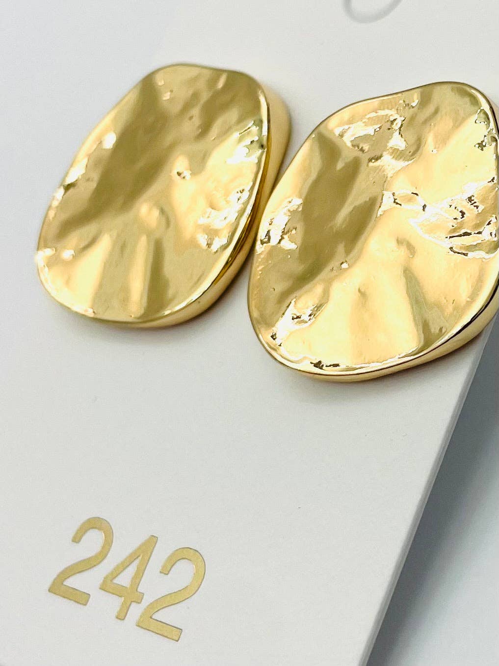 Gold earrings on a light gray background with number 242.