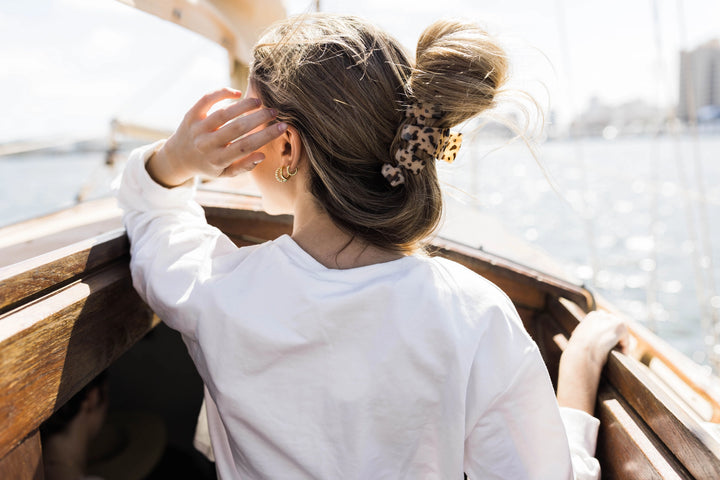 Woman with styled hair on a boat with water and cityscape in the background