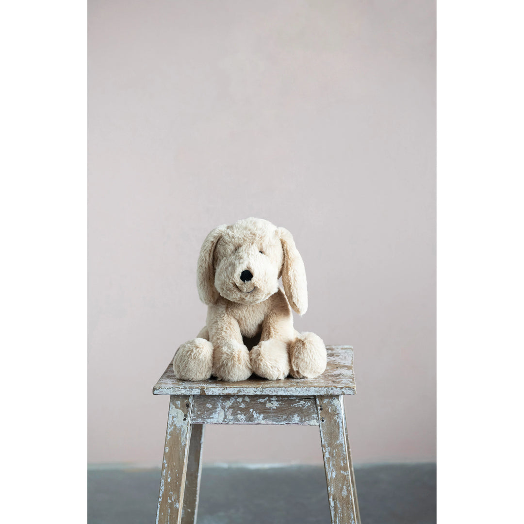 Stuffed dog toy on a wooden stool against a plain background