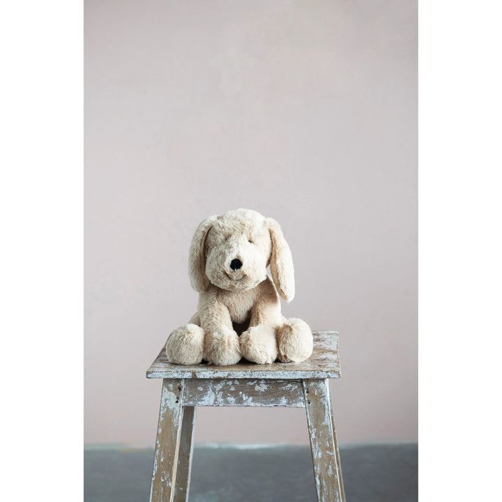 Stuffed dog toy on a wooden stool against a plain background