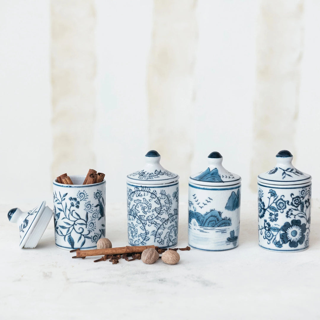 Set of four blue and white ceramic canisters with decorative patterns on a white background.