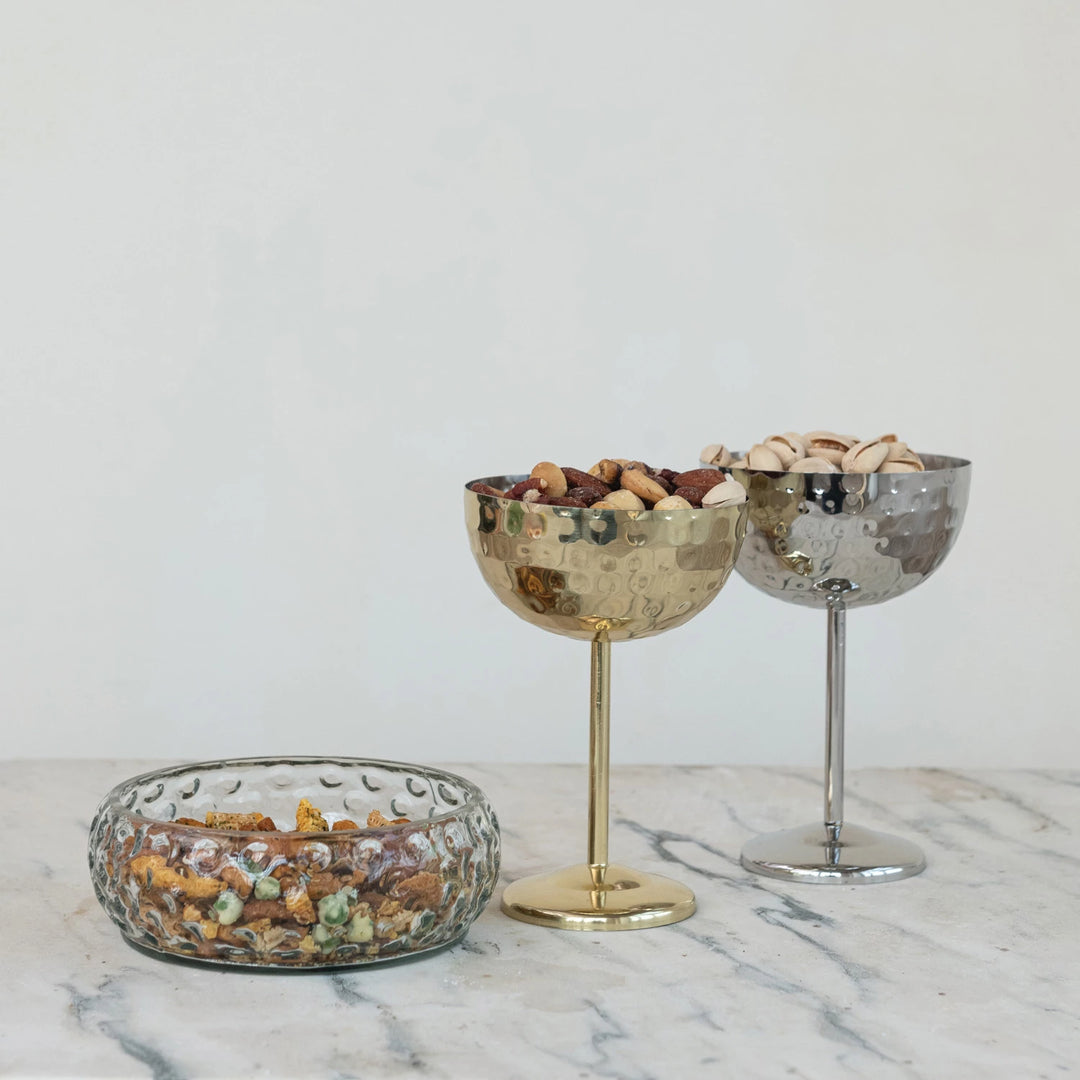 Three decorative bowls with snacks on a marble surface