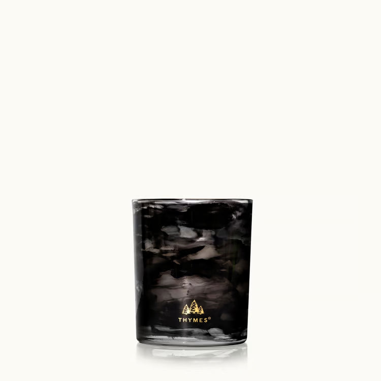 Noir Woods candle glowing in a dark styled setting with gift box