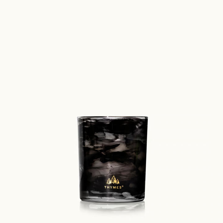 Noir Woods candle glowing in a dark styled setting with gift box