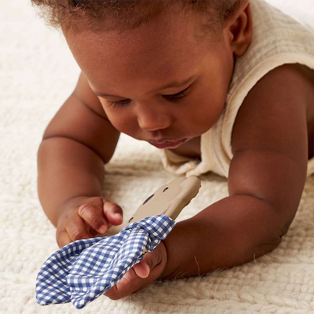 Baby playing with a blue and white checkered toy on a soft surface