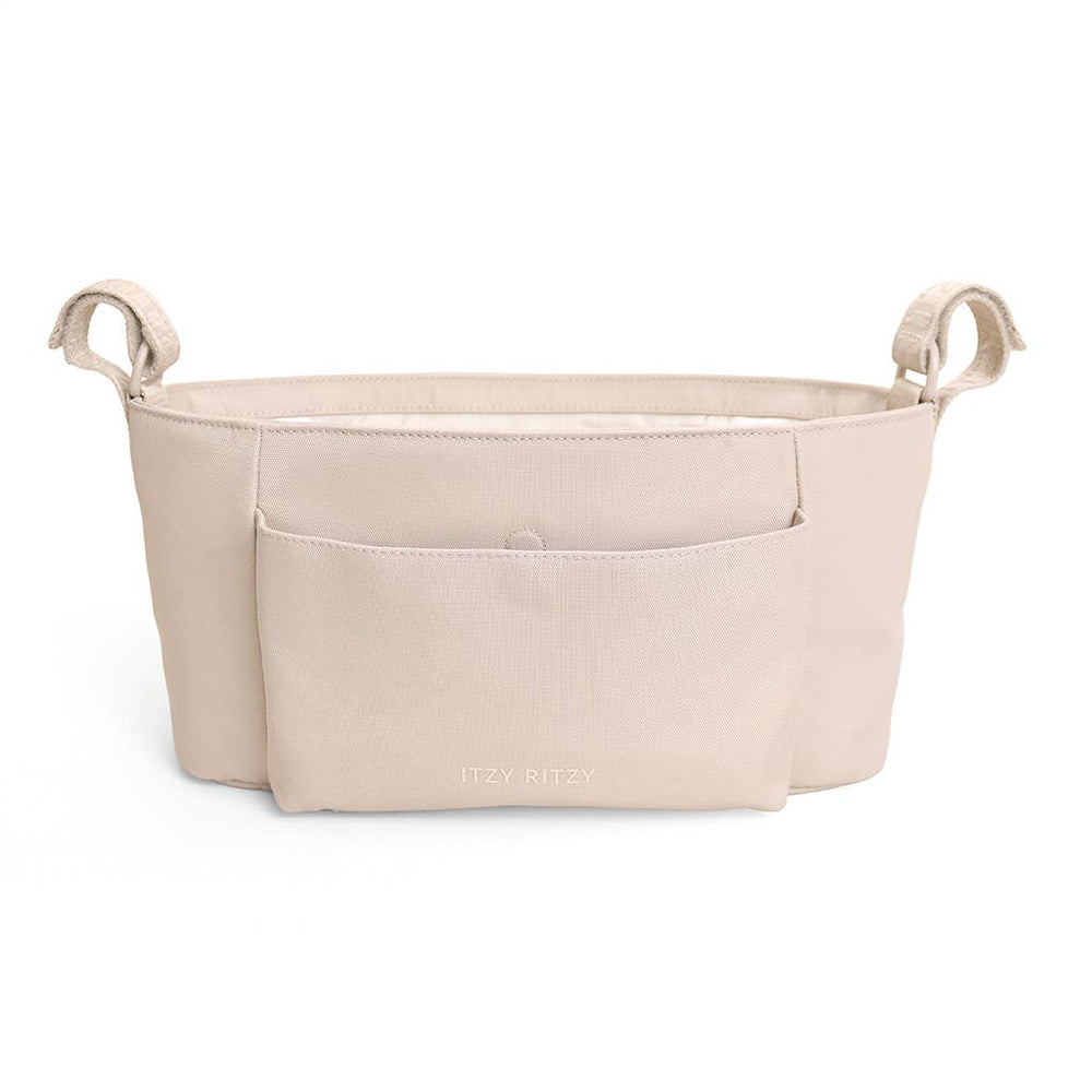 A light beige fabric baby carrier insert with two side handles and a front pocket, shown on a plain white background. The brand name 'ITZY RITZY' is subtly printed in white on the front pocket.