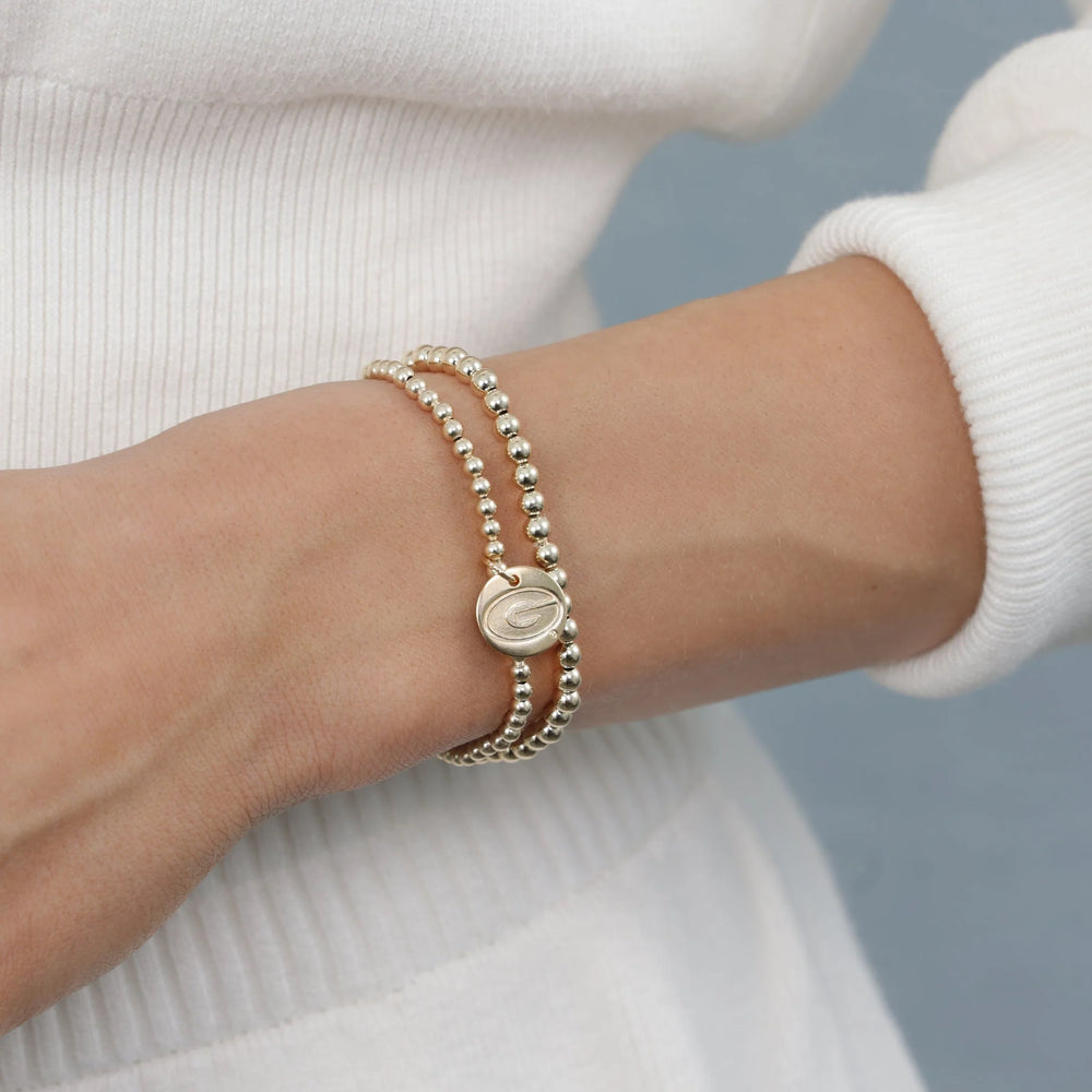 gold beaded bracelet with UGA logo charm on wrist - enewton