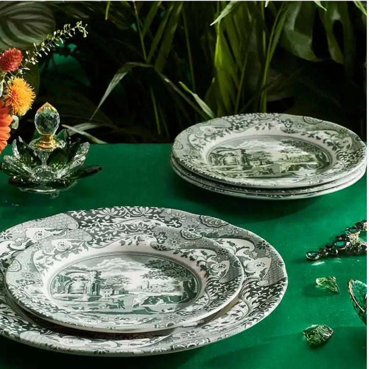 Decorative plates with intricate designs on a green surface with plants in the background