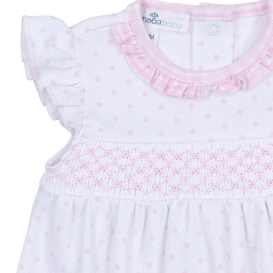 Baby dress with pink floral pattern and ruffled collar on a white background
