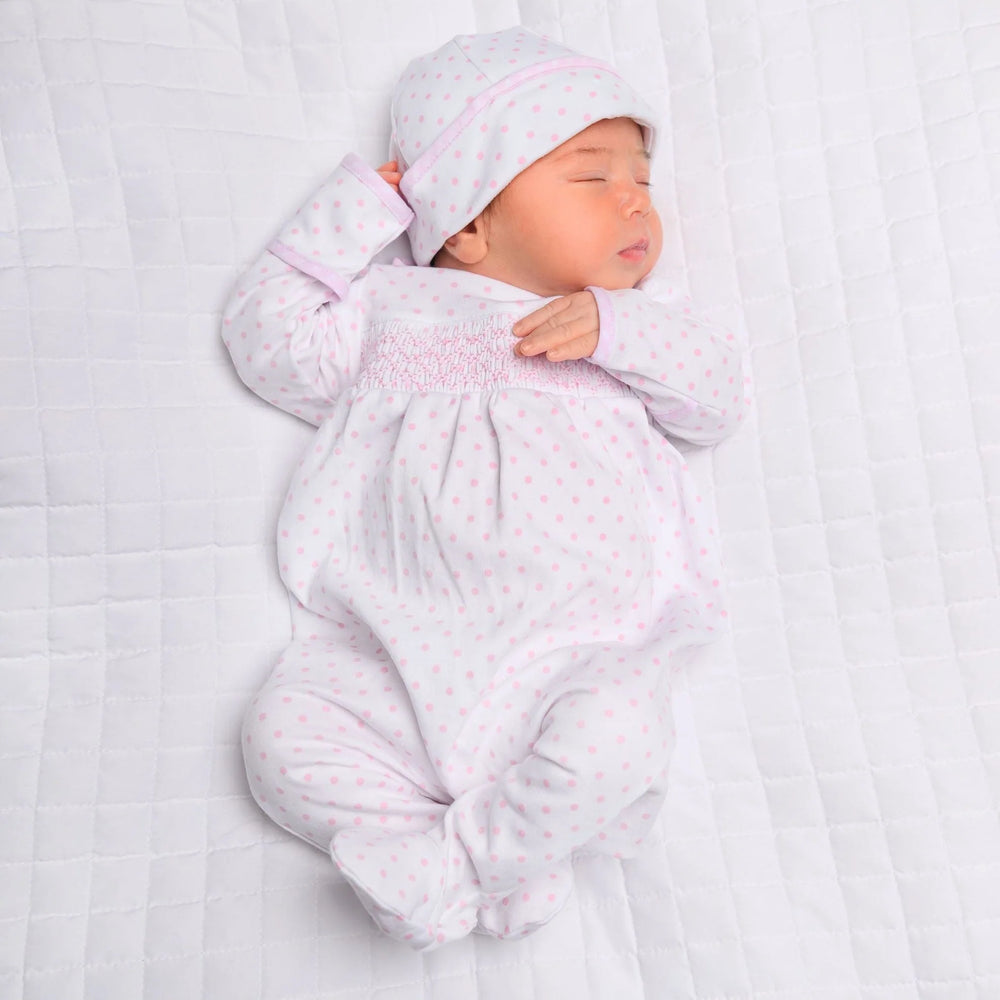 Newborn baby in a white outfit with pink patterns on a white background