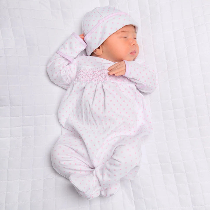 Newborn baby in a white outfit with pink patterns on a white background