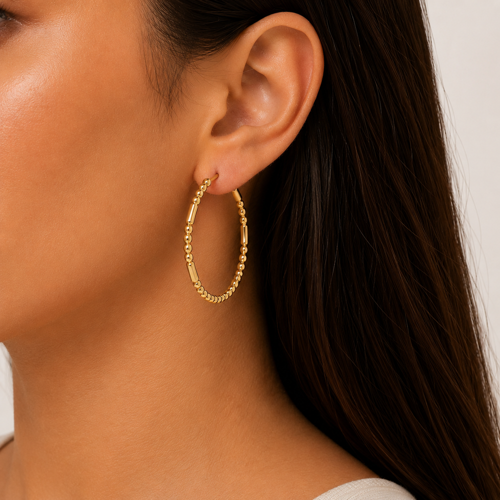 Gold hoop earring worn by a person with dark hair.