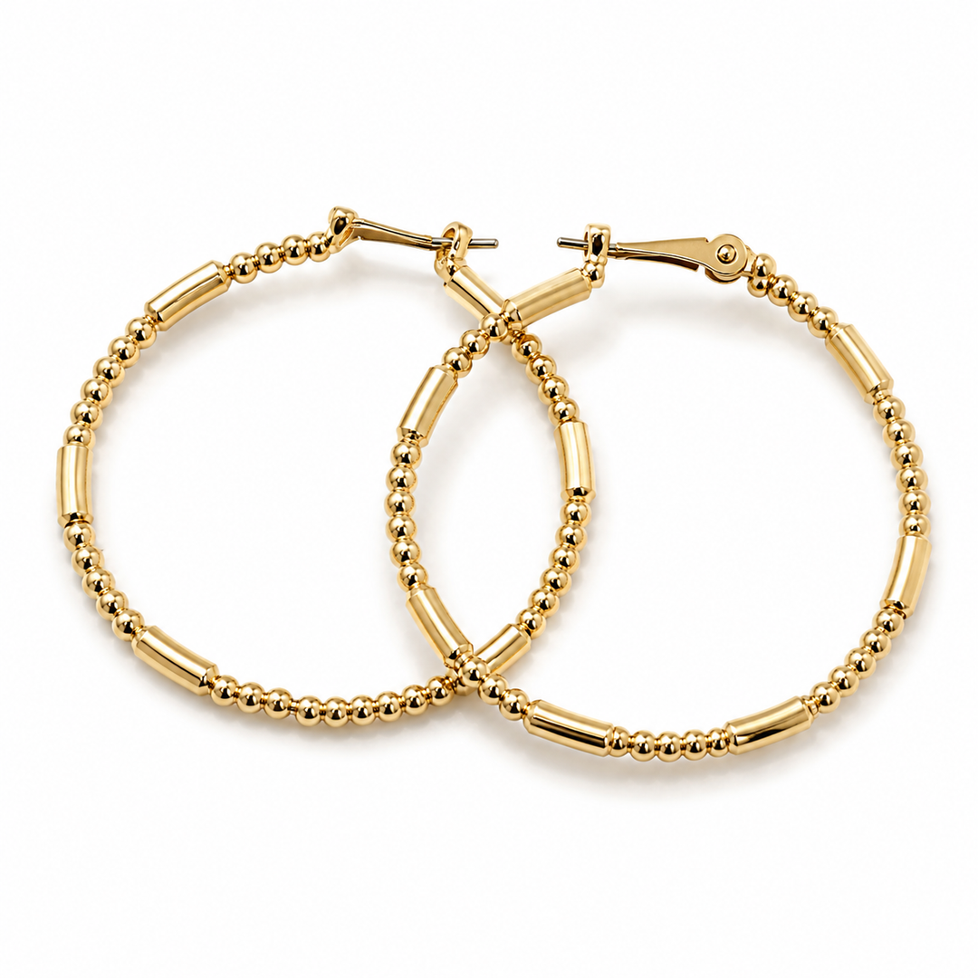 Gold hoop earrings with bead detailing on a white background
