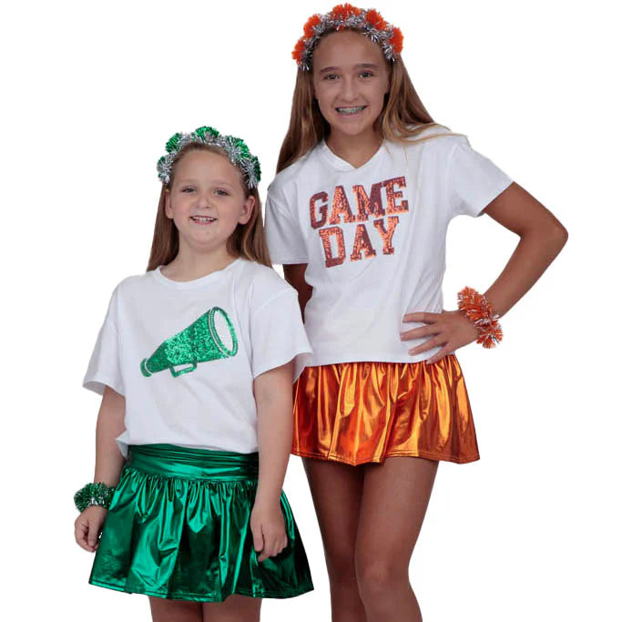 Two children in festive outfits with green and orange decorations on a white background