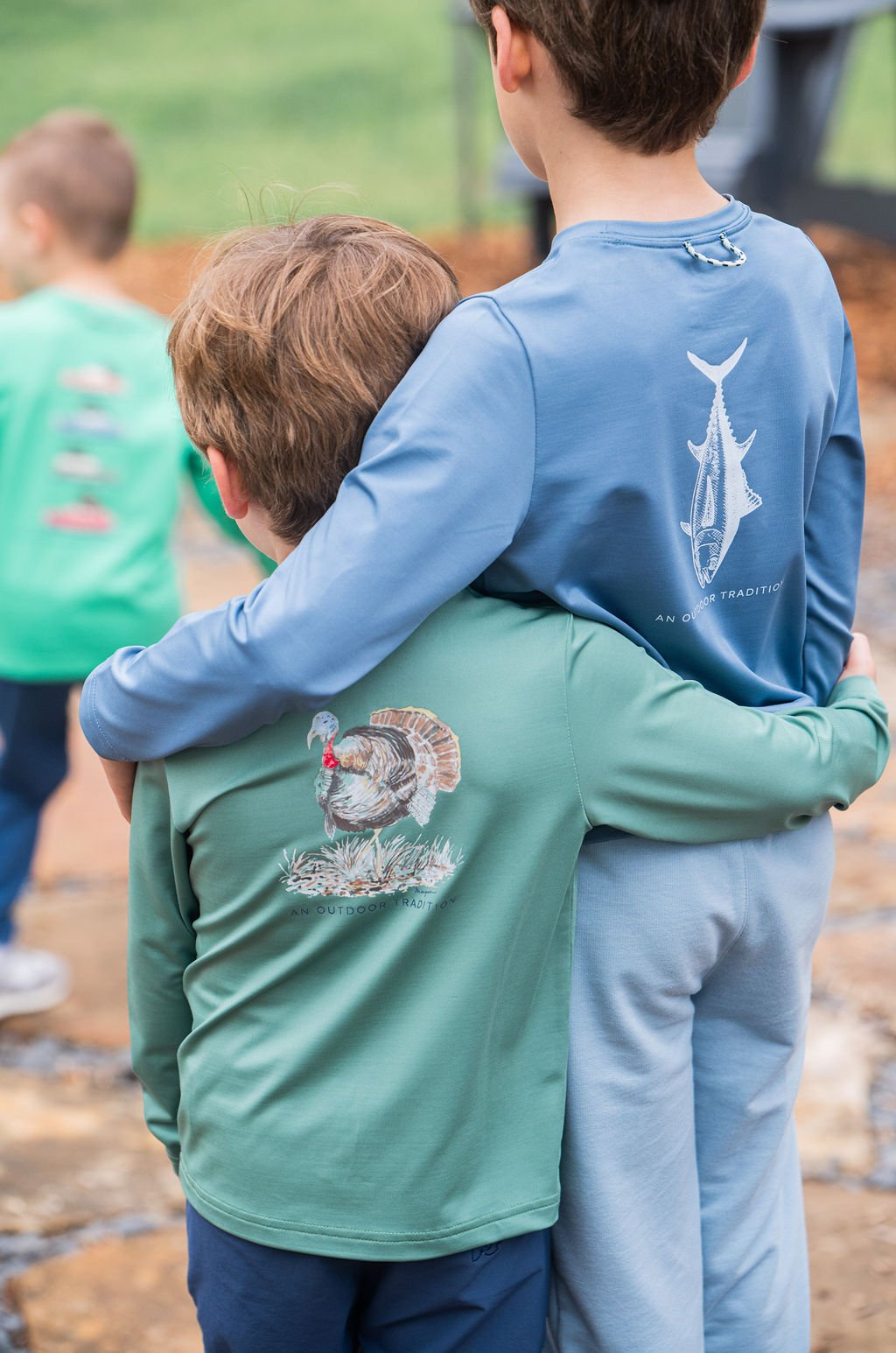 Two children wearing long-sleeve shirts with fish designs, standing close together.
