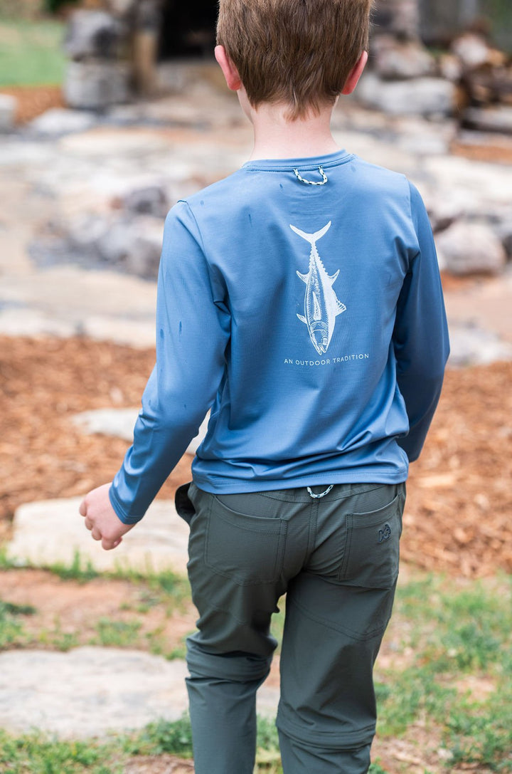 Person wearing a blue long-sleeve shirt with a white graphic on the back, standing outdoors.