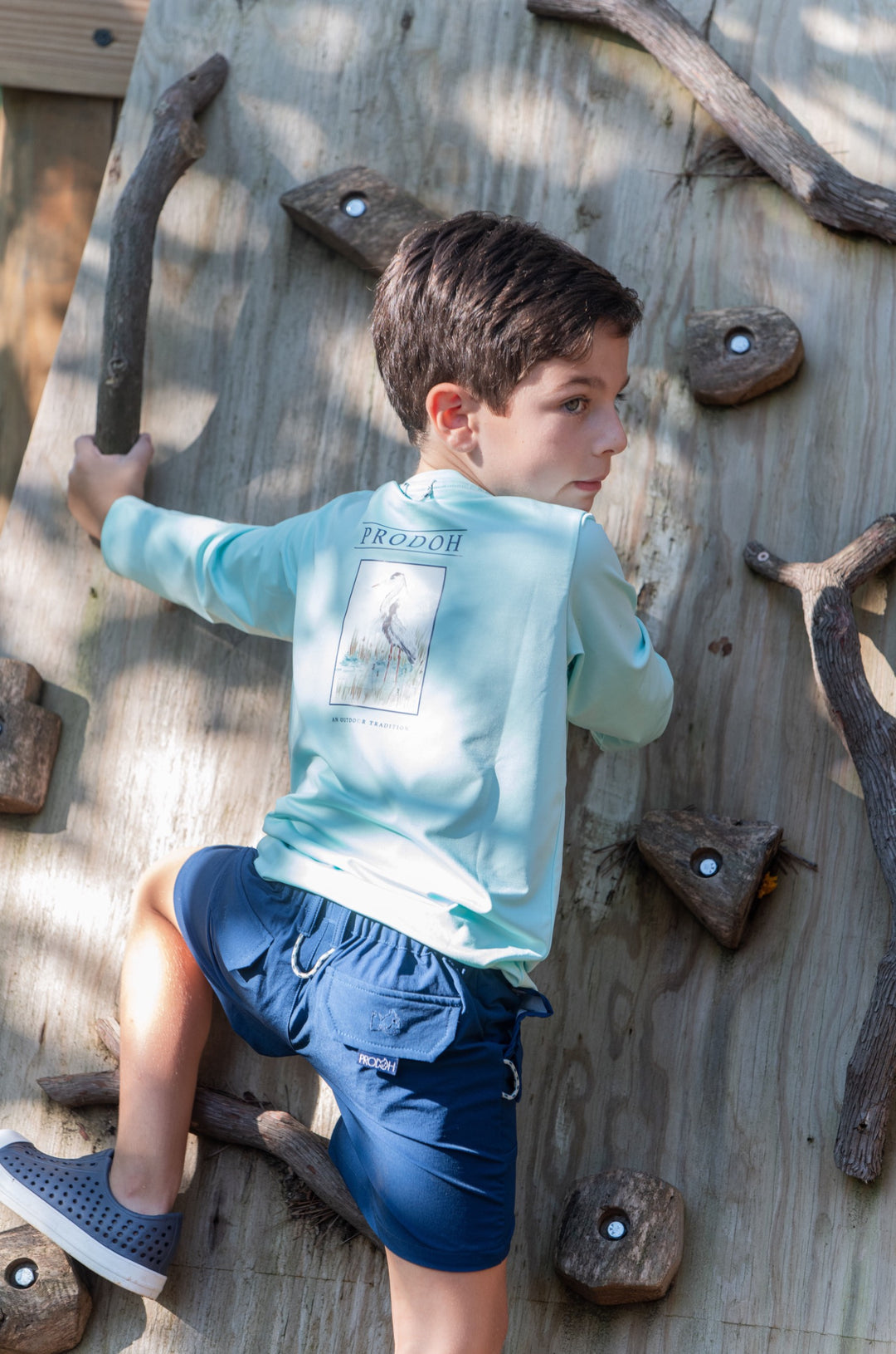 LITTLE BOY CLIMBING TREE IN LONG SLEEVE BLUE T-SHIRT