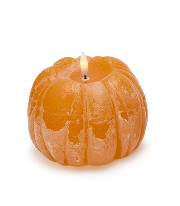 Pumpkin-shaped candle with a lit wick on a white background