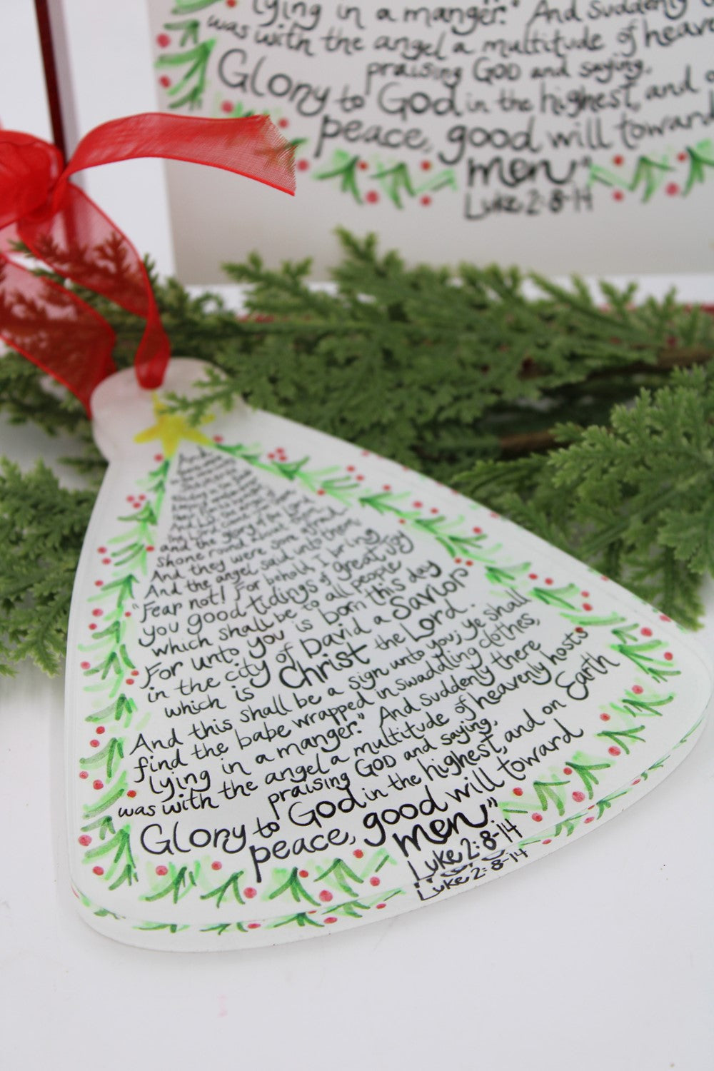 Decorative Christmas ornament with text and greenery in the background