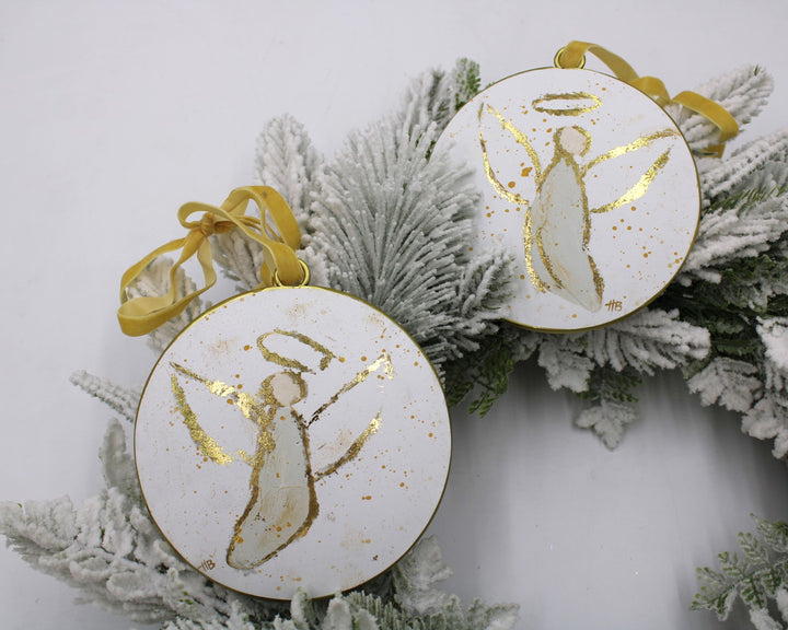 White Christmas ornaments with gold angel designs on a frosted branch background