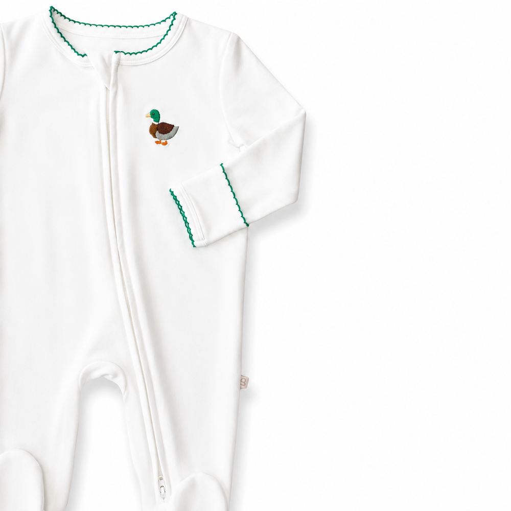 White baby onesie with green trim and a small embroidered mallard motif design on a white background