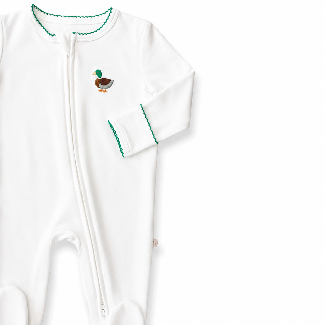 White baby onesie with green trim and a small embroidered mallard motif design on a white background