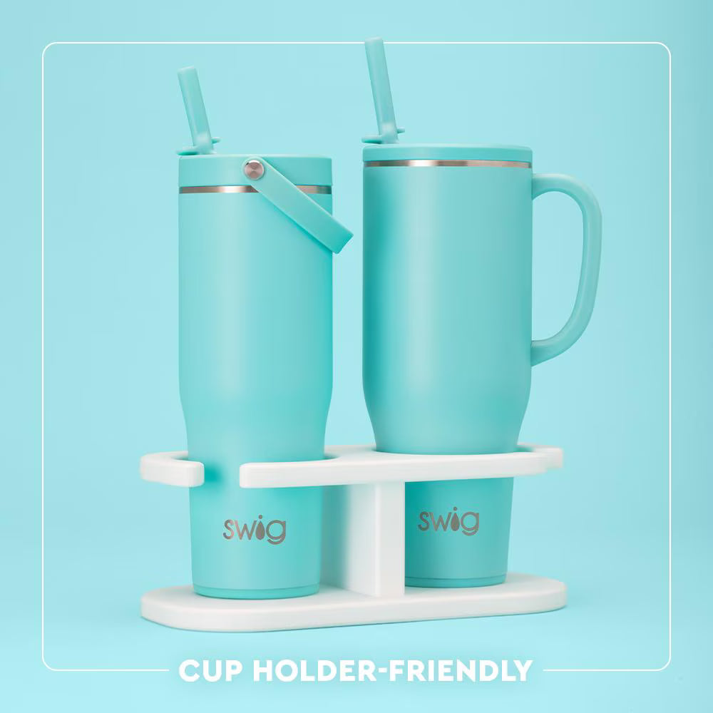 Two turquoise mugs with straws on a white stand against a light blue background, featuring the 'swig' brand.
