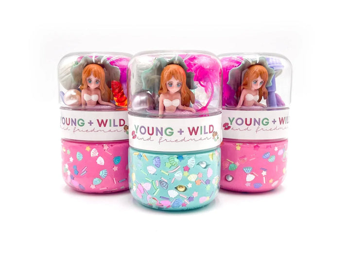 Three small containers with dolls inside, labeled 'Young + Wild', on a white background.