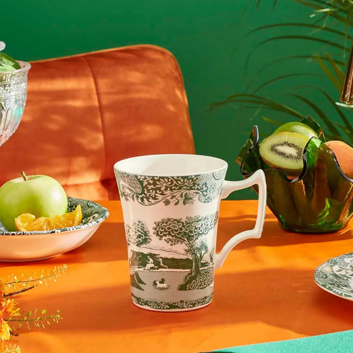 Decorative mug with nature-themed design on an orange surface with fruits and a green background