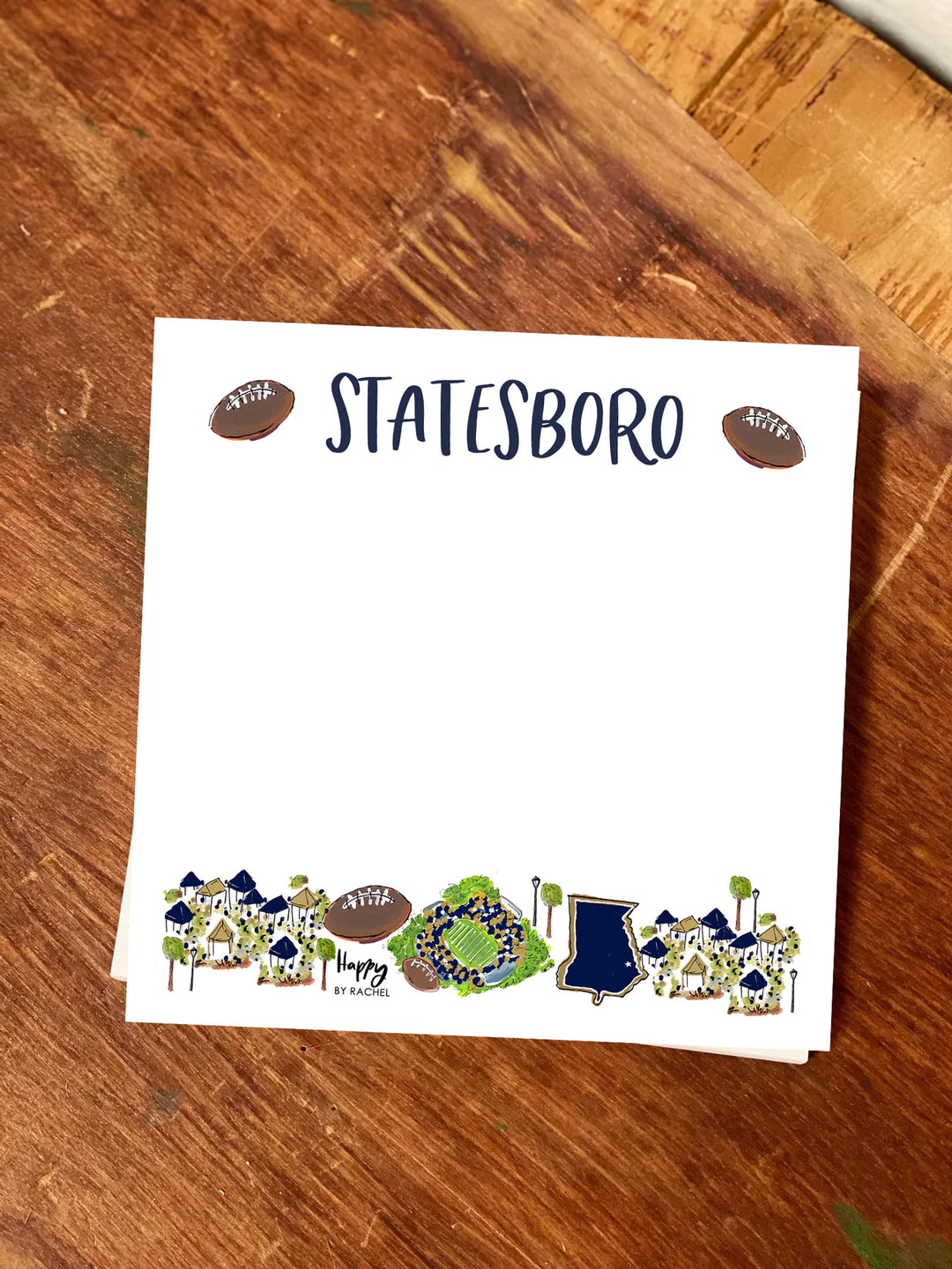 Note card with 'STATESBORO' printed on it, featuring illustrations of sports equipment and chairs, on a wooden surface.