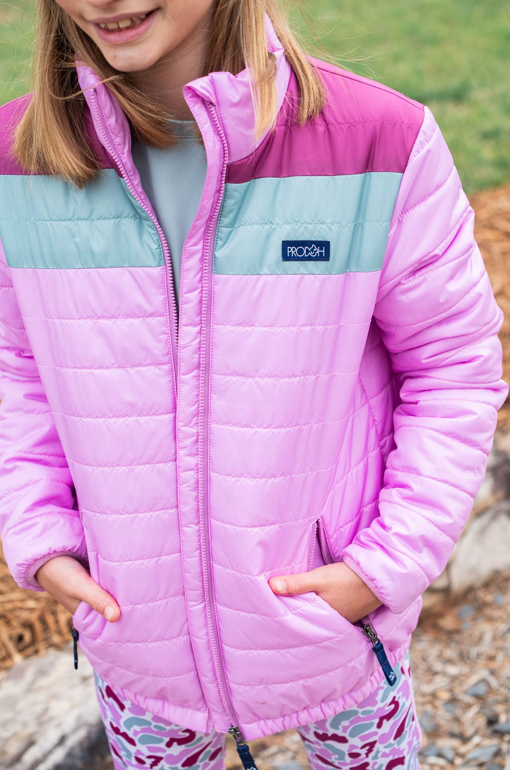 Child wearing a pink and light blue jacket with Patagonia logo outdoors.
