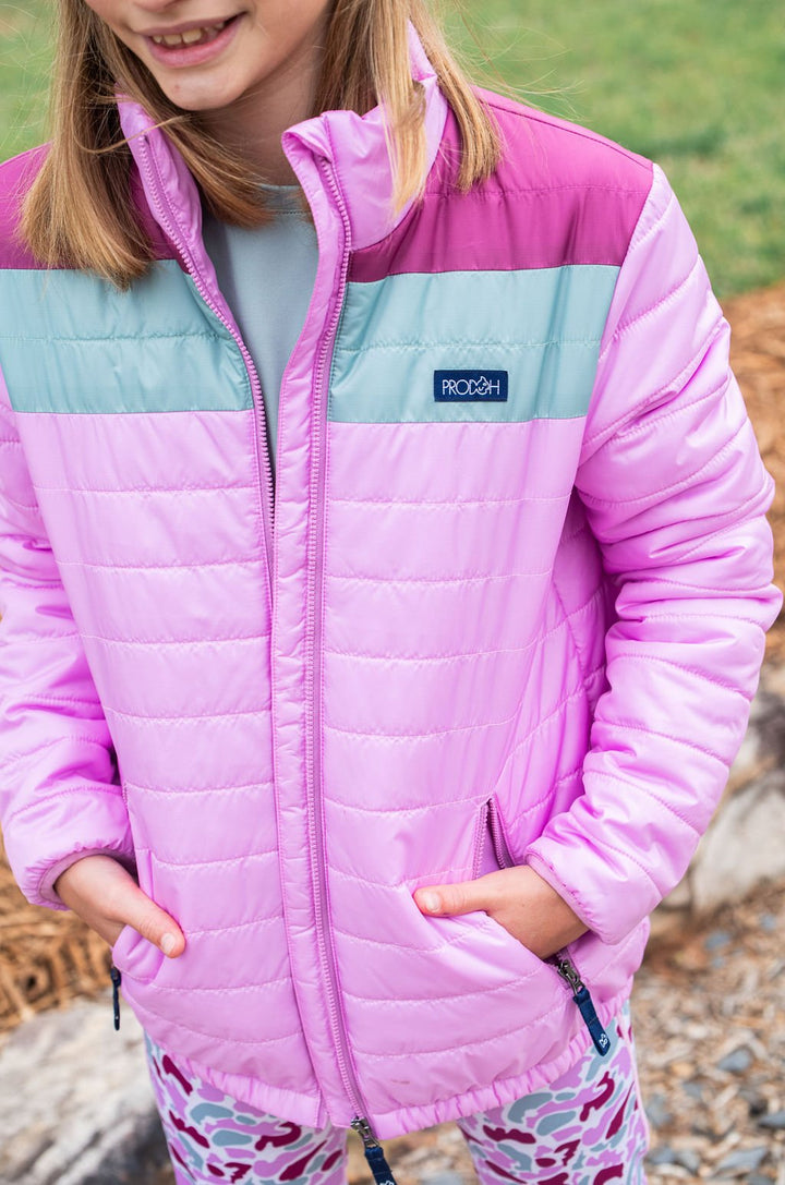 Child wearing a pink and light blue jacket with Patagonia logo outdoors.