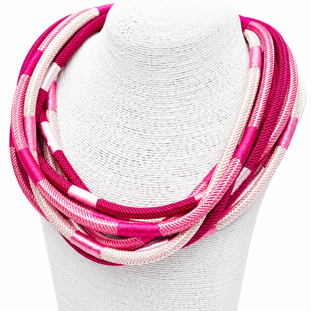 Necklace with pink and white braided cord on a white stand
