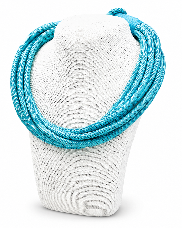 Turquoise necklace on a white textured stand against a white background