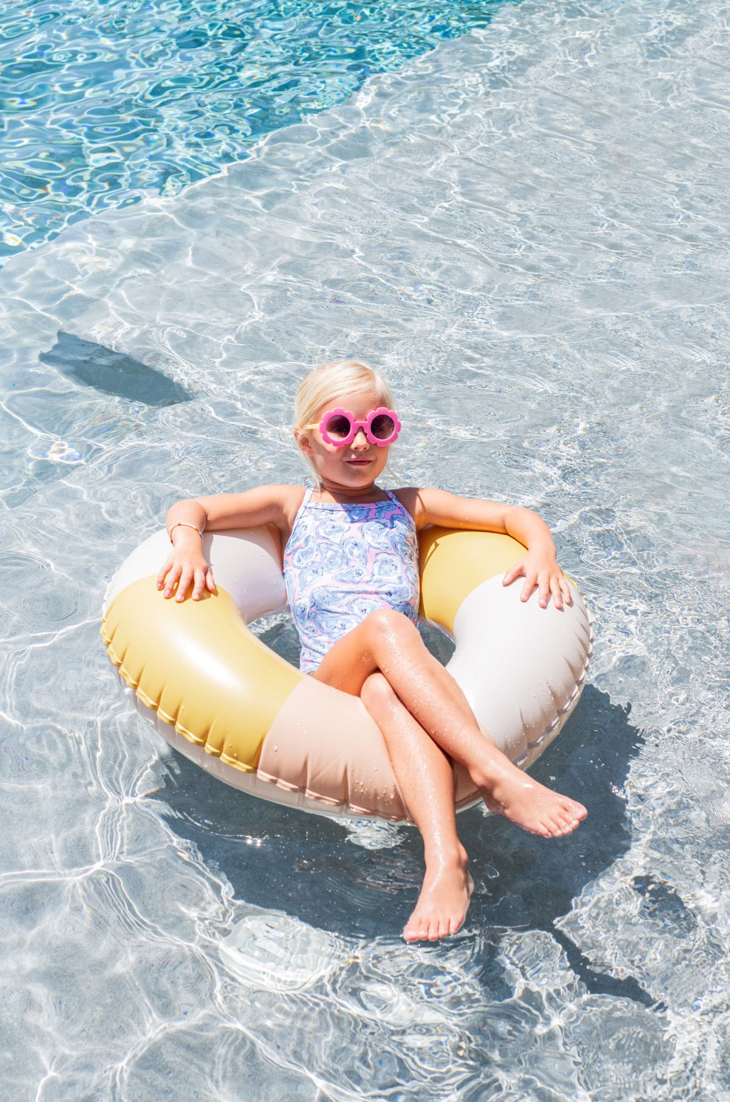 Child on a colorful inflatable ring in clear pool water