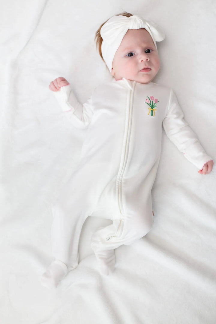 Baby in a white footie with a floral motif design on a white background