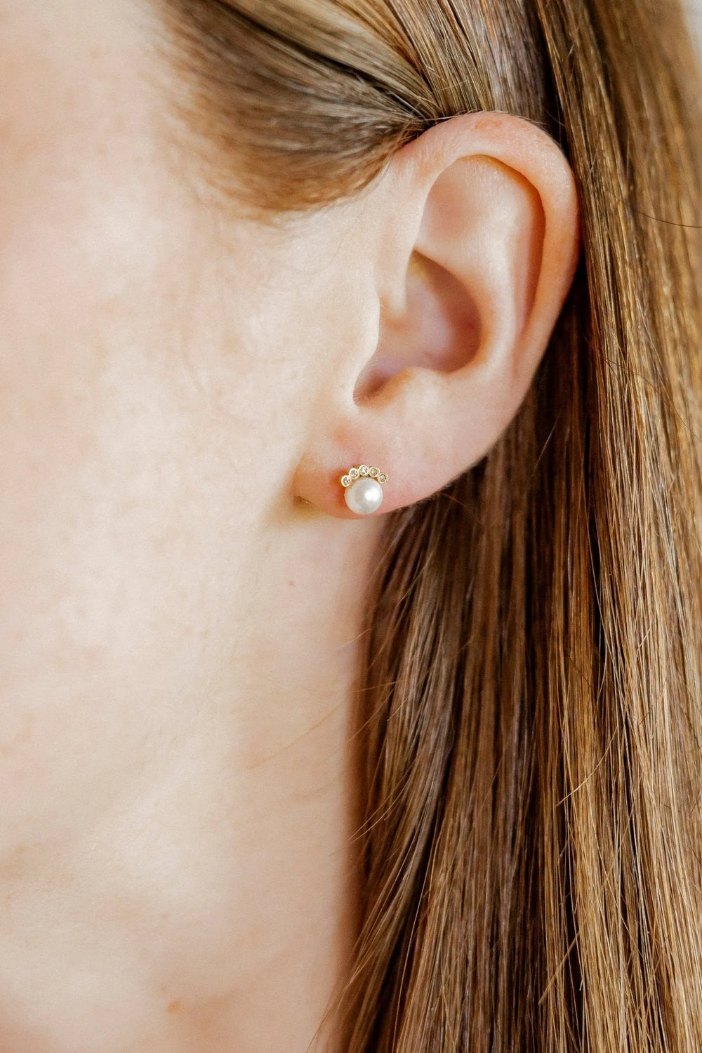 Winnie pearl and CZ gold screwback stud earring worn on the ear