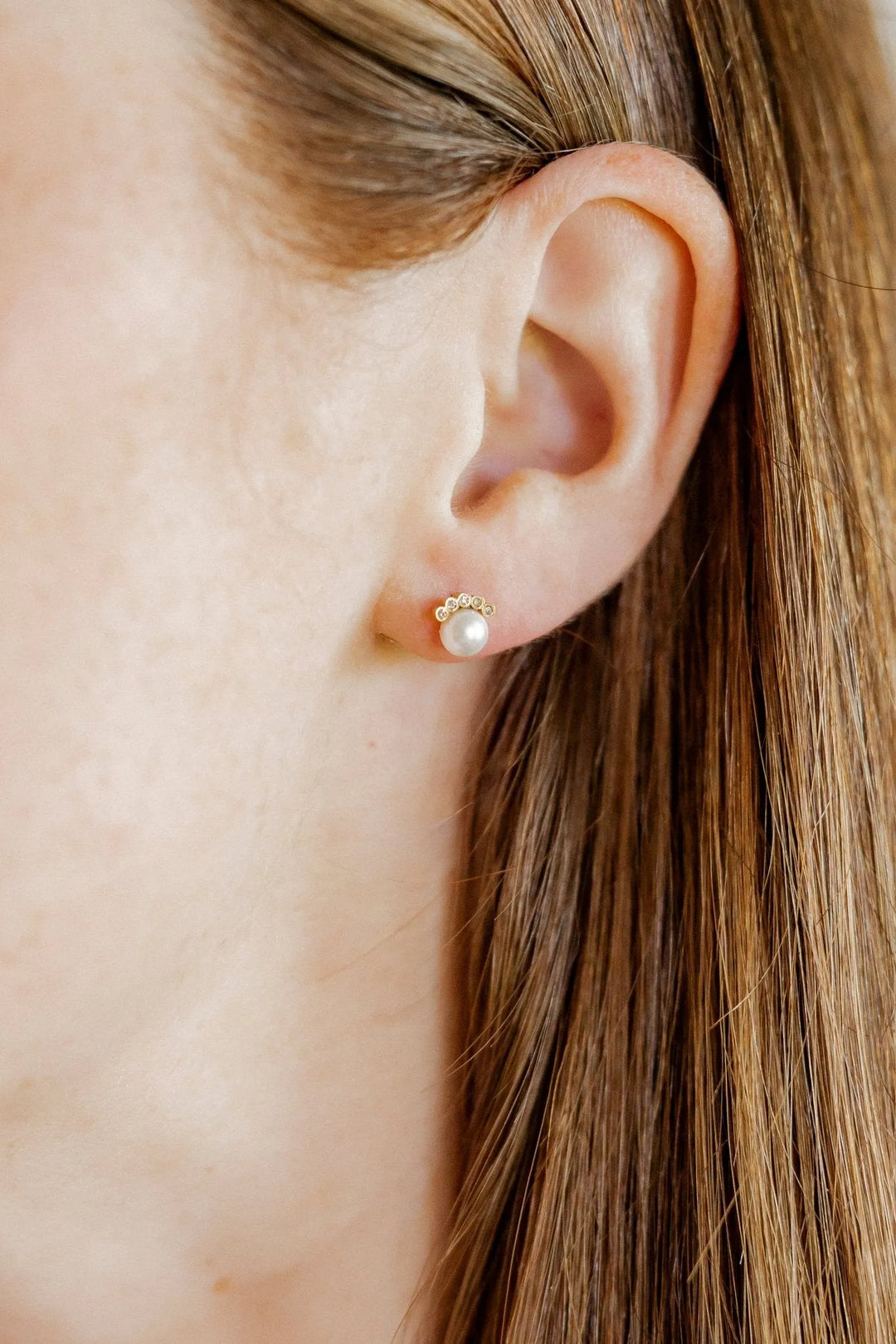Winnie pearl and CZ gold screwback stud earring worn on the ear