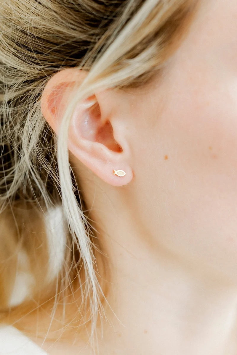 Ichthys gold fish screwback stud earring worn on the ear as a subtle faith accessory