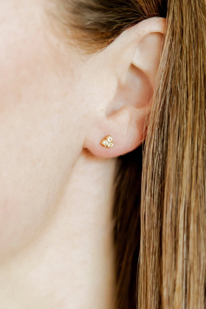 Tatum three-crystal gold screwback stud earring worn on the ear