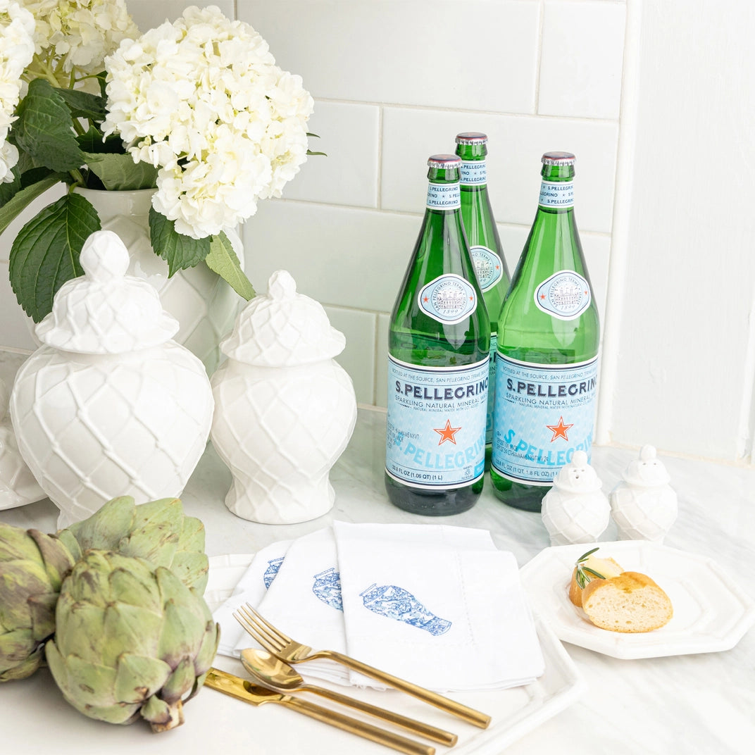 Two bottles of S.Pellegrino on a table with flowers and decorative items.