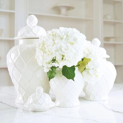 White ceramic vase with lid and white flowers on a light background