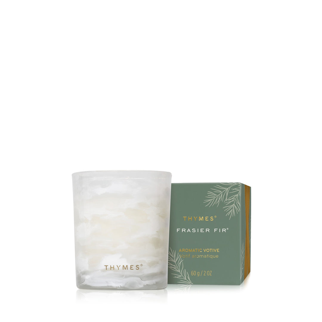 Frasier Fir Tidings 2 ounce votive candle in white marbled glass beside green gift box