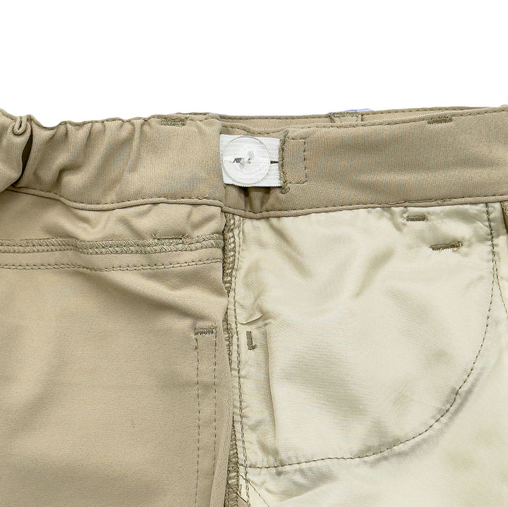 Close-up of beige pants with a brand label on a white background