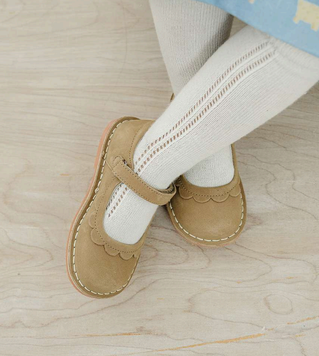 Children's beige shoes with white socks on a wooden floor