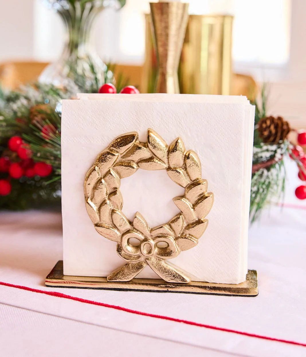Decorative gold wreath on a white card with Christmas decorations in the background