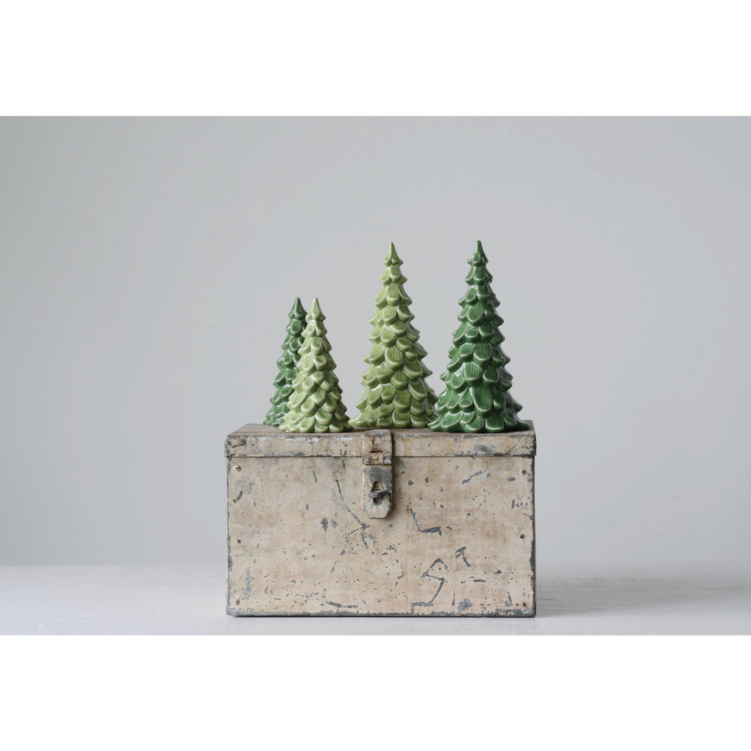 Three green Christmas trees in a rustic wooden box on a light gray background