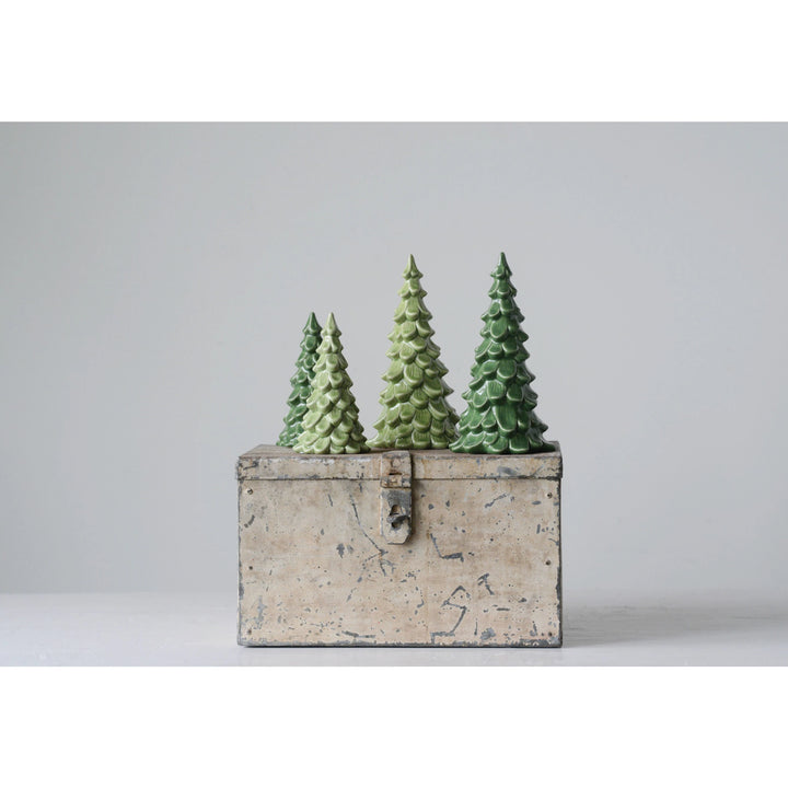 Three green Christmas trees in a rustic wooden box on a light gray background