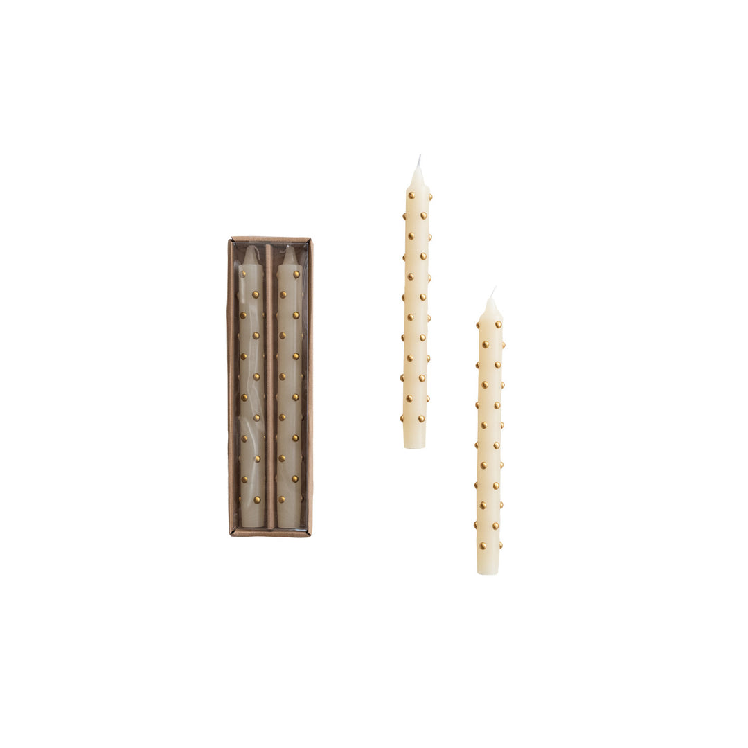 Set of tall, thin candles with decorative elements on a white background