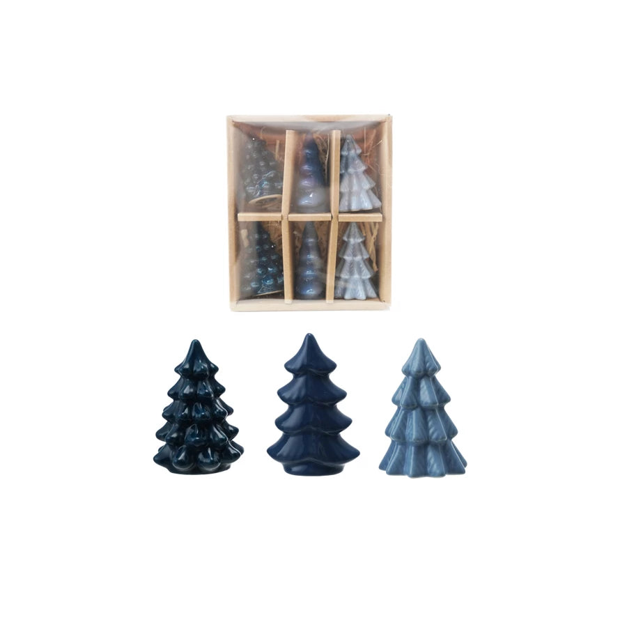 Set of three blue ceramic Christmas tree-shaped candles with a wooden box containing more candles on a white background.